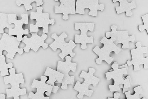 White jigsaw puzzle pieces on a grey background